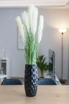 a black vase with grass in it on a table at City Life Athens Apartments in Athens