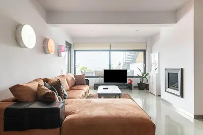 a living room with a brown couch and a tv at Magnificent, Deluxe Villa, Lagonisi, Athens Riviera in Áyios Nikólaos
