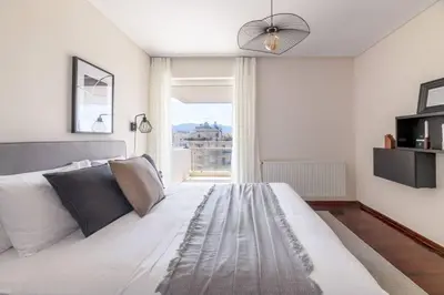 a bedroom with a large white bed with a large window at Serene 2BR Apartment in Alimos with Sea view by UPSTREET in Athens