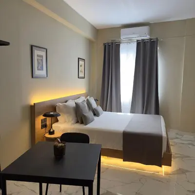 a bedroom with a bed and a table and a window at Potnia Athens in Athens