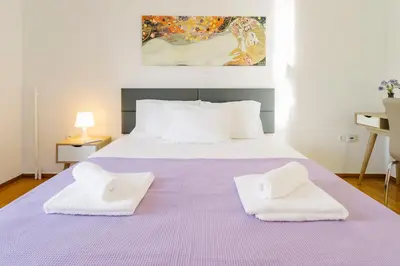 a white bed with two white towels on it at Acropolis view apartment in Athens in Athens