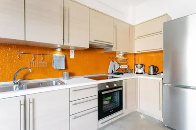 a kitchen with white cabinets and an orange wall at Acropolis view apartment in Athens in Athens