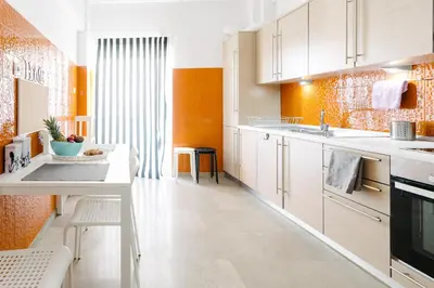 a kitchen with white cabinets and an orange wall at Acropolis view apartment in Athens in Athens
