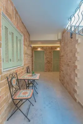 a patio with two chairs and a table and a brick wall at The Stone Manor , Noho boutique Thissio in Athens