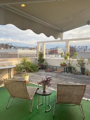 a patio with two chairs and a table on a roof at Sacred Way rooftop apartment in Athens