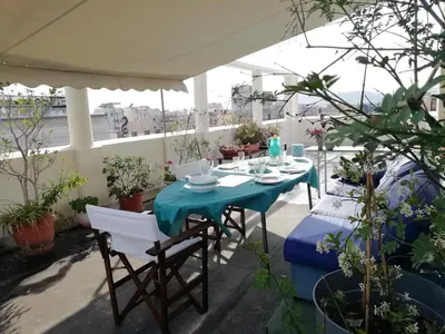 a table and chairs on a balcony with plants at Sacred Way rooftop apartment in Athens