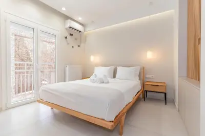 a white bedroom with a large bed and a window at Sunny & Luxurious Penthouse with Terrace in Athens