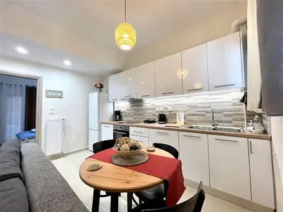 a living room with a table and a couch and a kitchen at Elegant & Modern Flat Near Panathenaic Stadium in Athens