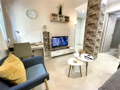 a living room with a blue couch and a tv at Elegant & Modern Flat Near Panathenaic Stadium in Athens