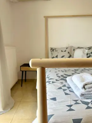 a bed with a wooden frame in a bedroom at Kallikratis Apartment Near Athens Airport in Spáta