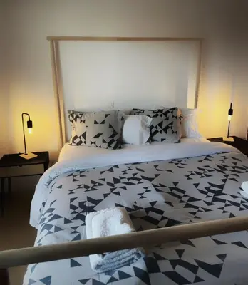 a bedroom with a bed with a black and white comforter at Kallikratis Apartment Near Athens Airport in Spáta