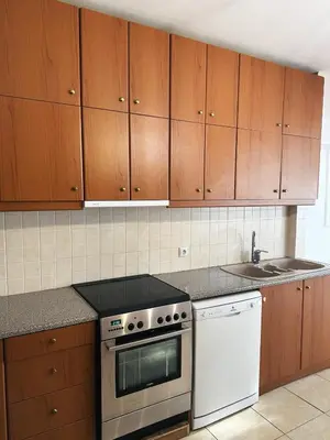 a kitchen with wooden cabinets and a stove and a sink at Kallikratis Apartment Near Athens Airport in Spáta