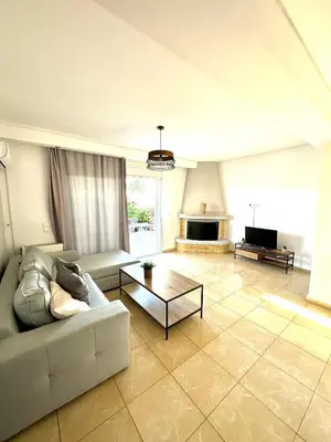 a living room with a couch and a tv at Kallikratis Apartment Near Athens Airport in Spáta