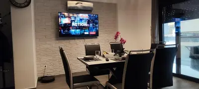a room with a table with chairs and a tv on the wall at Jacuzzi Suite and Family Apartment Near Acropolis in Athens