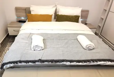 a large bed with white sheets and pillows at Jacuzzi Suite and Family Apartment Near Acropolis in Athens