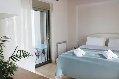a white bedroom with a blue bed and a plant at Elizabeth Studio in Athens