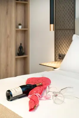 a bottle of wine and a pair of glasses on a bed at Electra Urban Apartment Athens in Athens
