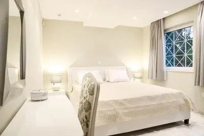 a white bedroom with a bed and a window at Mikaella Residence in Athens