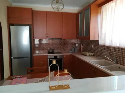 a kitchen with brown cabinets and a sink and a refrigerator at GLYFADA APARTMENT 