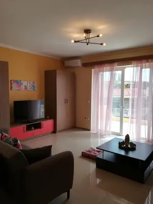 a living room with a couch and a table and a tv at GLYFADA APARTMENT 