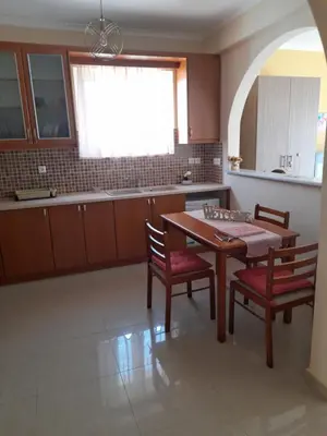 a kitchen with a wooden table and two chairs and a table and a window at GLYFADA APARTMENT 