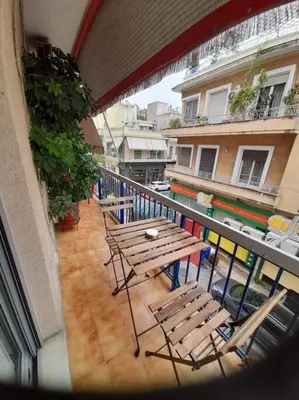 a balcony with wooden tables and chairs on a building at Eleni’s House near to Thisio in Athens