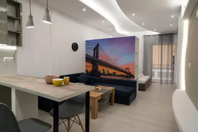 a living room with a blue couch and a bridge painting on the wall at Lenorman Apartments in Athens
