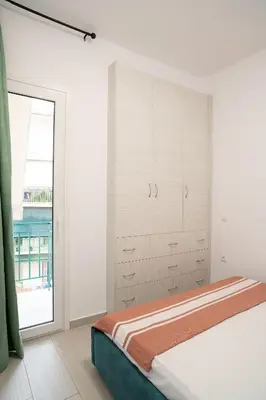 a white bedroom with a bed and a window at Lenorman Apartments in Athens