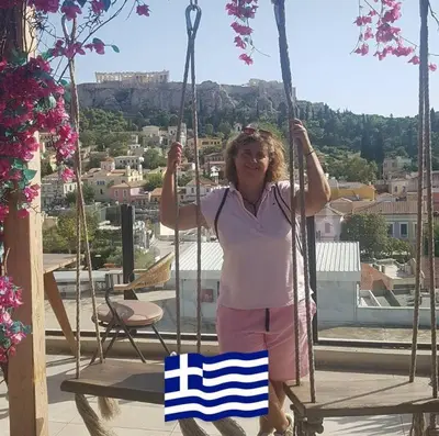 a woman standing on a swing with a greek flag at Athens Marialena Apartment in Athens