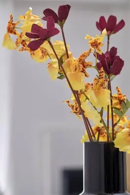 a black vase filled with purple and yellow flowers at Chic Apt with All Comforts in the Heart of Athens! in Athens