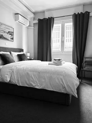 a bedroom with a large bed and a window at Pnoé d Athéna in Athens