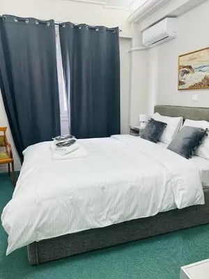 a bedroom with a large white bed with blue curtains at Pnoé d Athéna in Athens