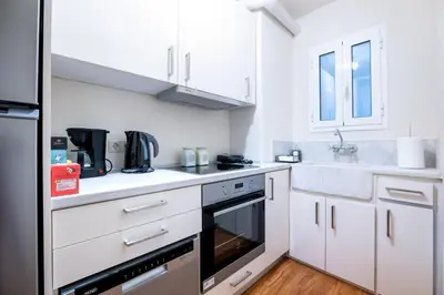 a kitchen with white cabinets and a black appliance at Glamorous Apt in Kolonaki in Athens
