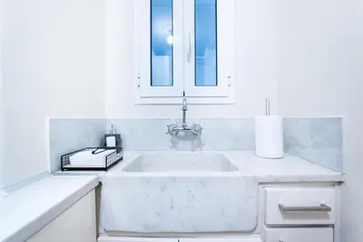 a white kitchen with a sink and a window at Glamorous Apt in Kolonaki in Athens