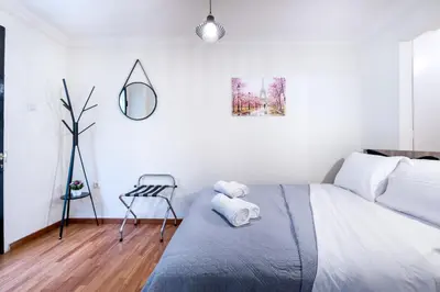 a white bedroom with a bed and a chair at Glamorous Apt in Kolonaki in Athens