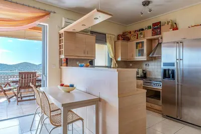 a kitchen with a table and a stainless steel refrigerator at Anavissos Seaview Holiday Home in Anavissos