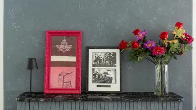 a table with a vase of flowers and pictures at Bunny island- seaview house, private garden , Lagonisi, Attika riviera by Comfortbnb in Lagonissi