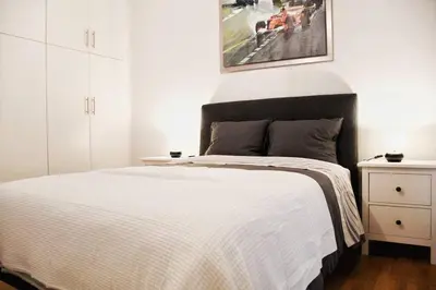 a bedroom with a large white bed with a picture on the wall at central Athens apartment near Kallimarmaro hosted by vasiliki in Athens