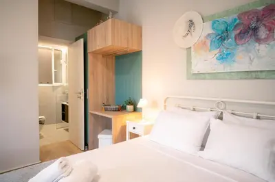 a bedroom with a white bed and a bathroom at Peacock's Apartments in Piraeus