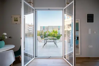 a sliding glass door leading to a balcony with a table at Peacock's Apartments in Piraeus