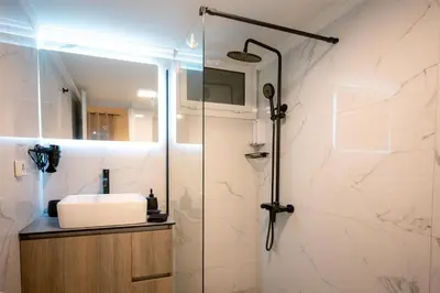 a bathroom with a sink and a shower at Peacock's Apartments in Piraeus