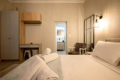 a bedroom with a white bed and a fireplace at Peacock's Apartments in Piraeus