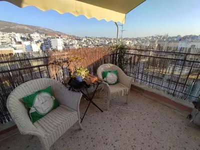 a patio with two chairs and a table on a balcony at Eagle's Nest Acropolis View in Athens