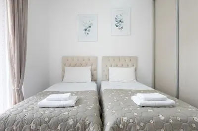 two beds in a bedroom with white walls at ILIADA Luxury Apartment in Porto Rafti
