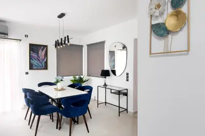 a dining room with blue chairs and a table at ILIADA Luxury Apartment in Porto Rafti