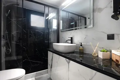 a black and white bathroom with a sink and a toilet at ILIADA Luxury Apartment in Porto Rafti
