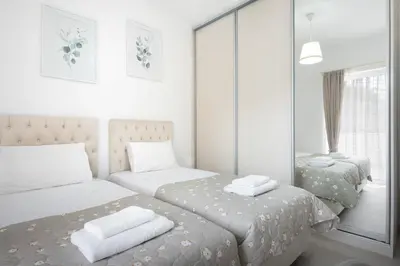 a white bedroom with two beds and a mirror at ILIADA Luxury Apartment in Porto Rafti