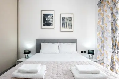 a bedroom with a large white bed with two pillows at ILIADA Luxury Apartment in Porto Rafti