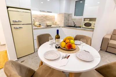 a white table with a bowl of fruit and a bottle of wine at Lux Residence Near Acropolis VIPGreece in Athens