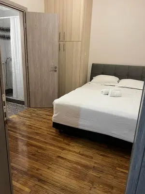 a bedroom with a bed with white sheets and a wooden floor at Evita's cozy apartment in Athens